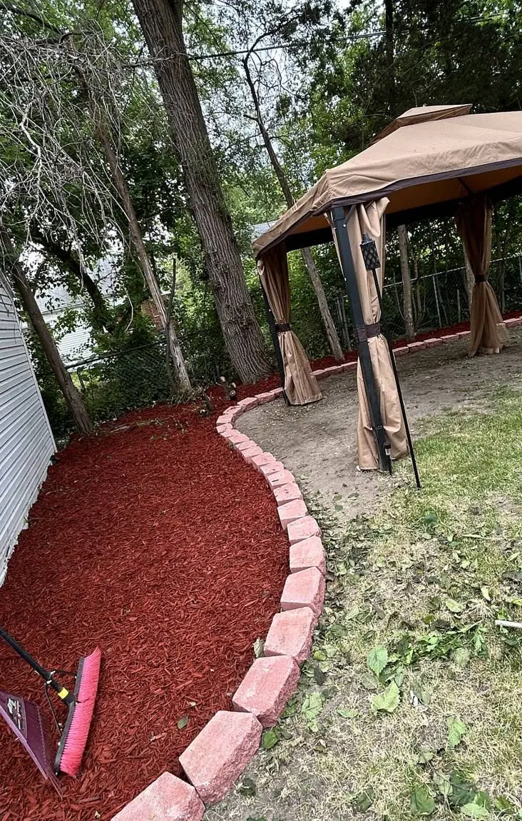 New red mulch bed with block edging beside a gazebo